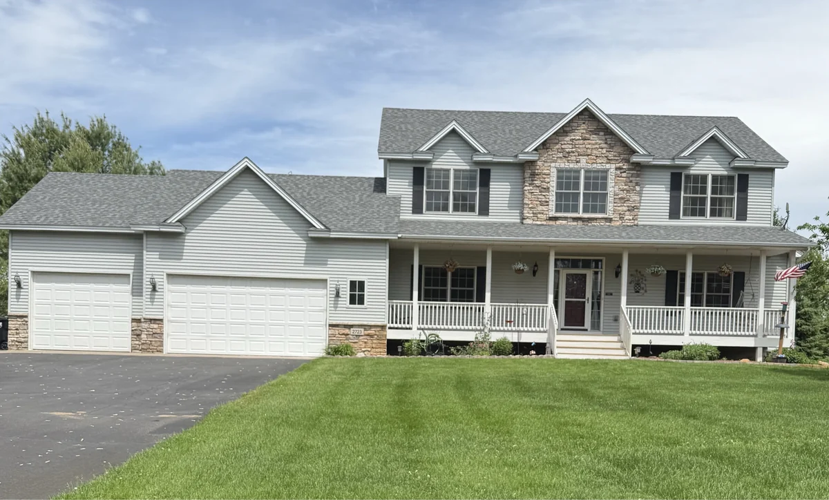 A large two-story home in Andover with a three-car garage, covered porch and a wide mown lawn