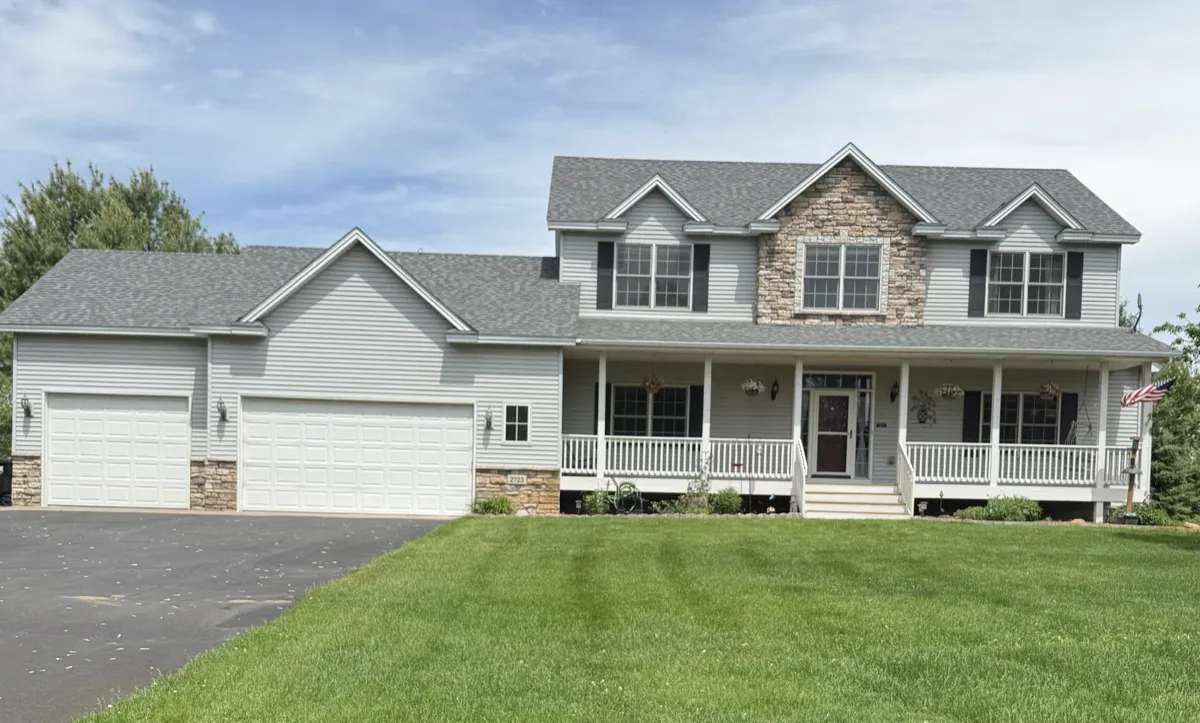 Two-story home with white garage doors, a covered porch and a mown lawn