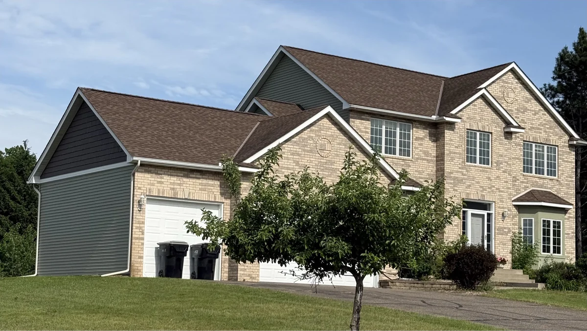 A large brick two-story seen from the side, showing the depth of the house and the lot