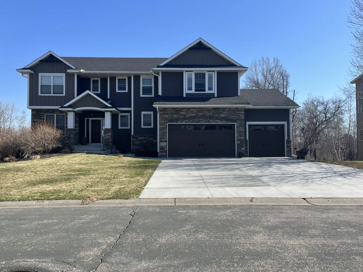 A dark navy newer two-story home with a wide concrete driveway on an Arden Hills street
