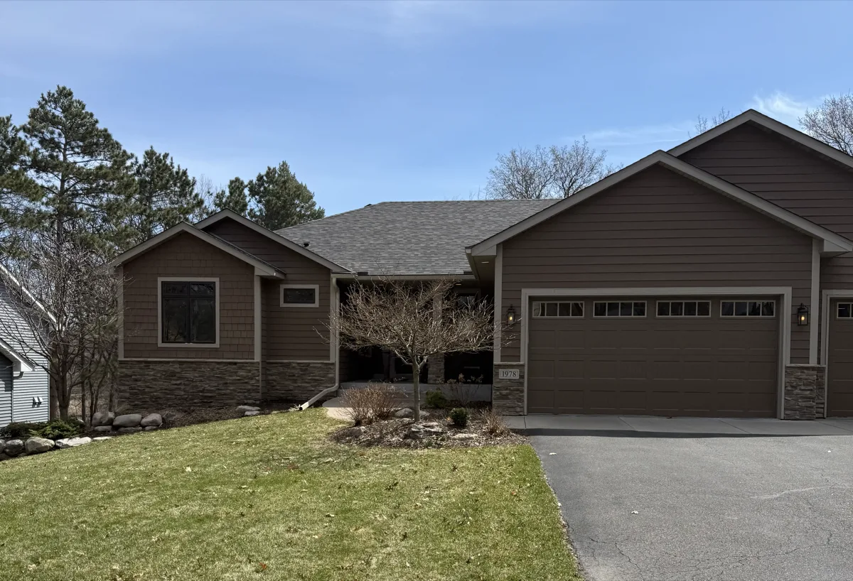 A brown walkout rambler with stone accents set among mature pines in Arden Hills