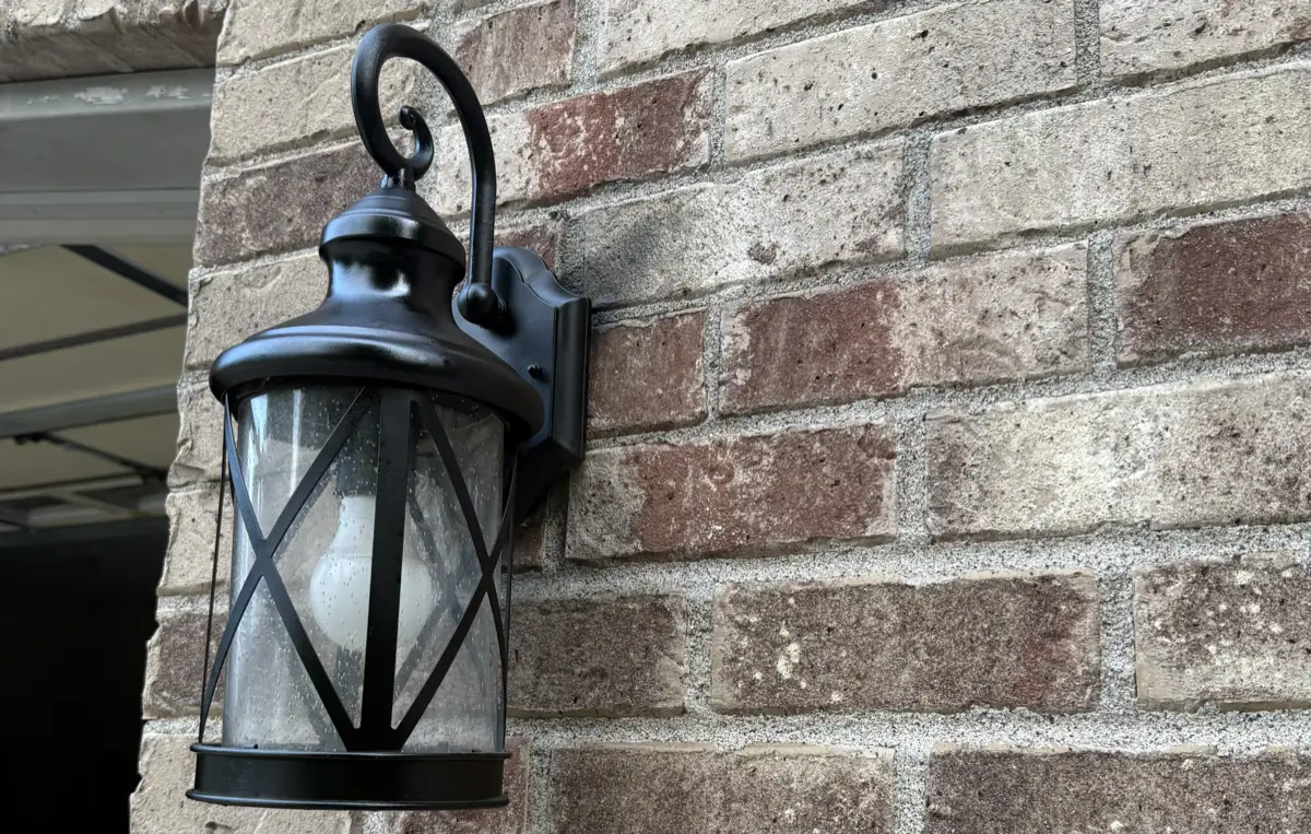 A new black exterior coach light mounted on a brick wall