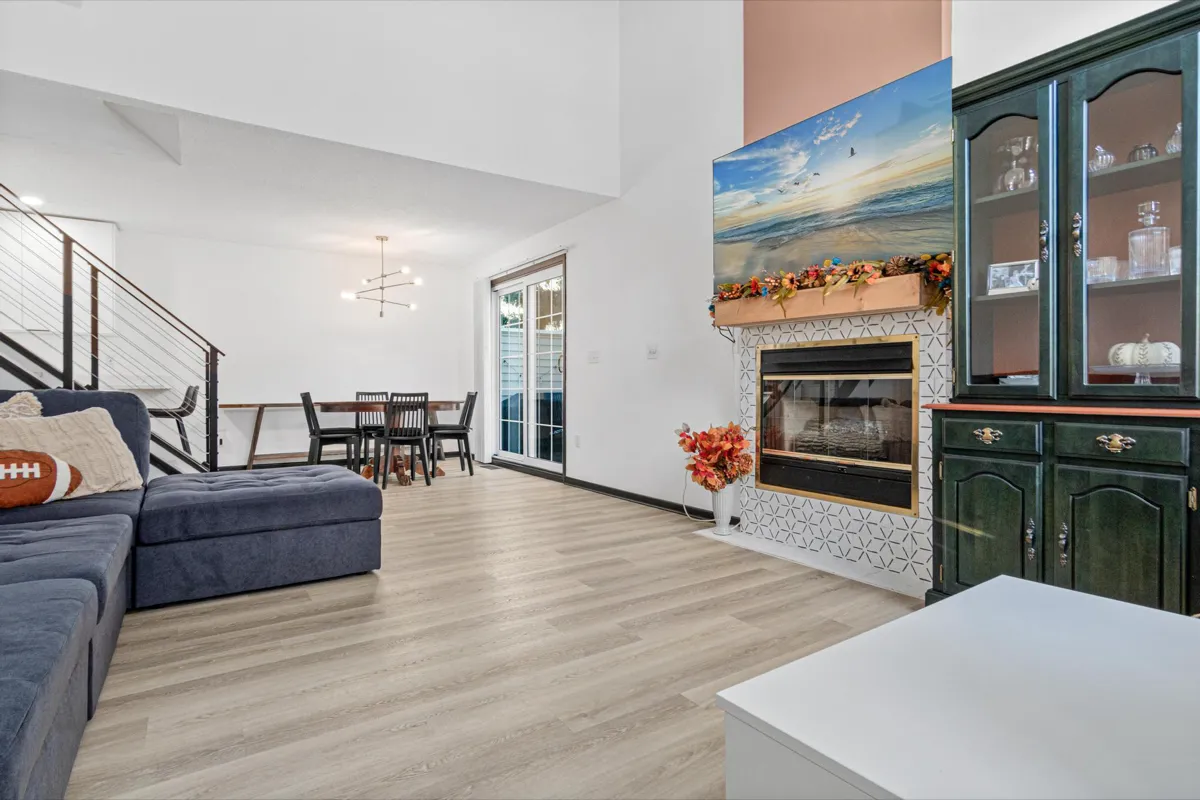 Living room with a tiled fireplace and built-in cabinetry beside a staircase