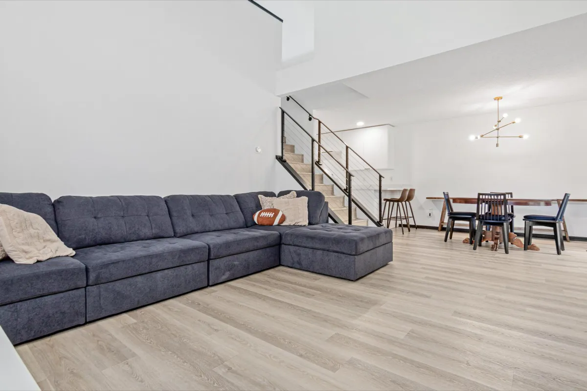 Open living and dining area with vaulted ceiling and light wood flooring