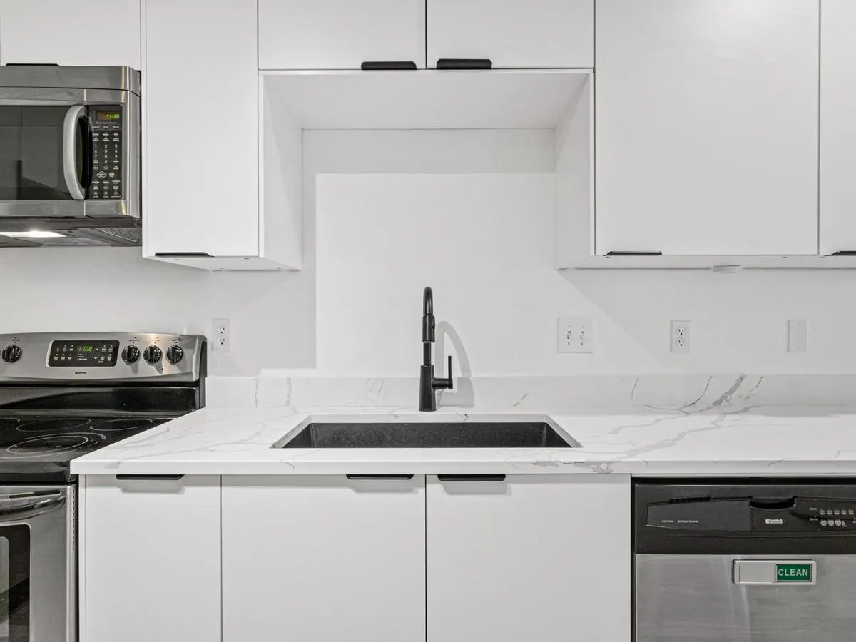 Refreshed white kitchen with marble-look counters, black fixtures, and stainless appliances