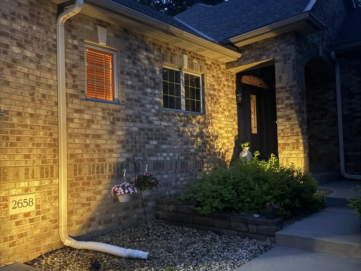 A brick home lit warmly at dusk in the Sanctuary neighborhood of Blaine