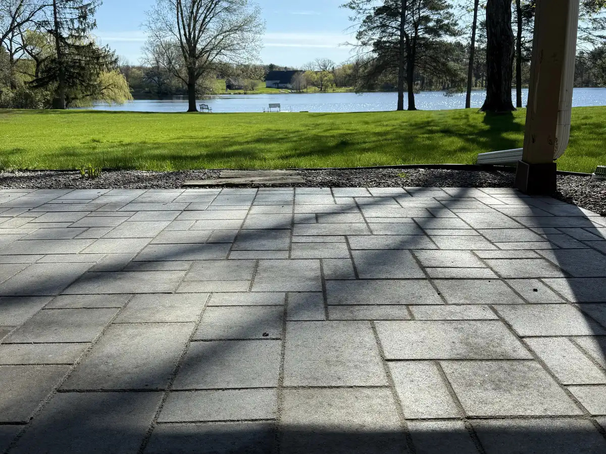 Paver patio looking across a lawn to a lake framed by trees in Blaine