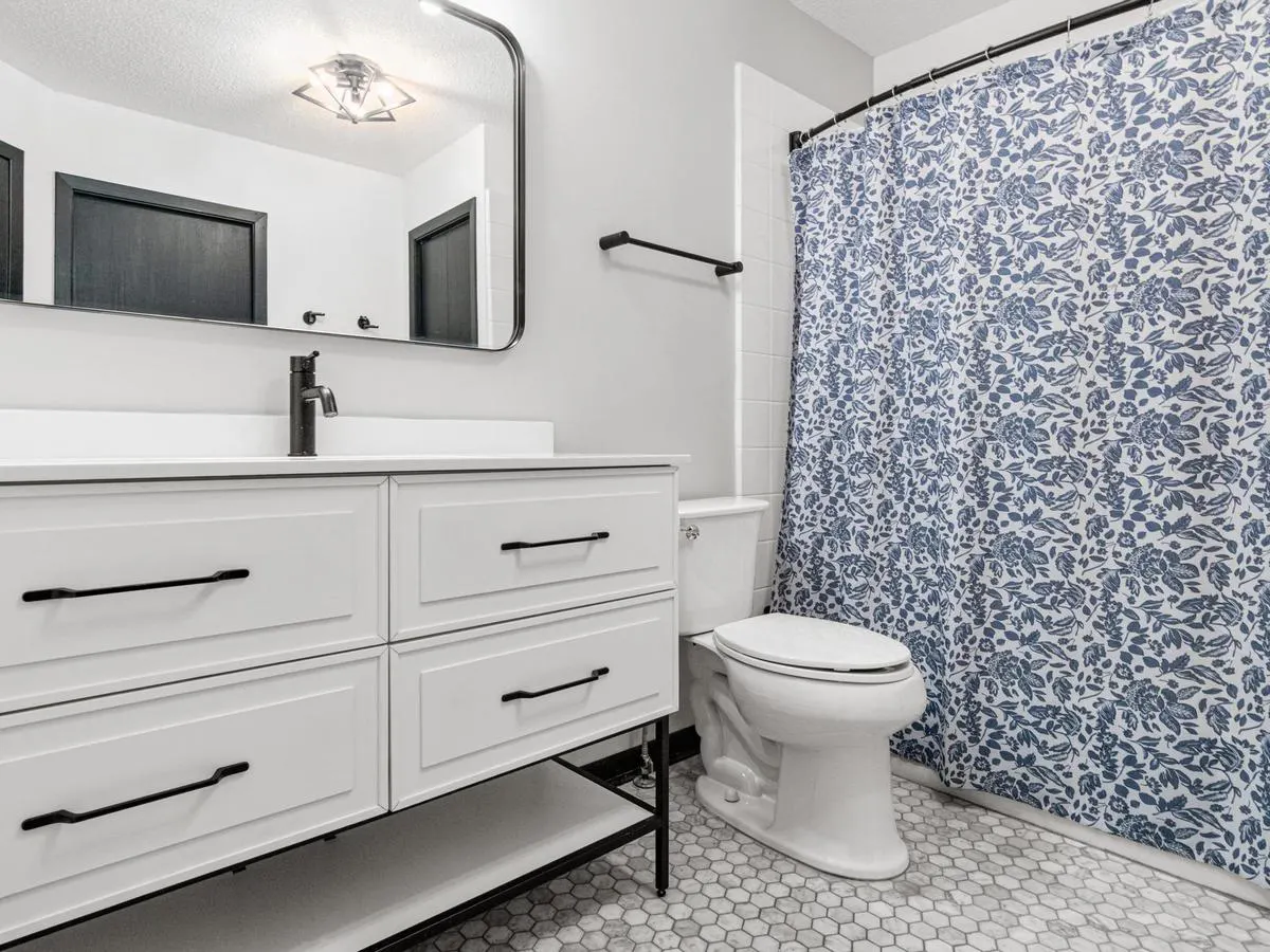 Updated bathroom with a white vanity, black fixtures, and tiled floor